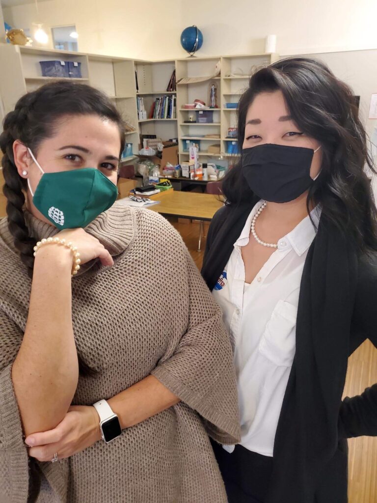 Two teachers in masks pose together for a photo
