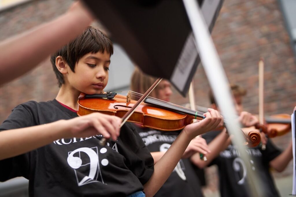 Middle school students play their violin during orchestra practice.