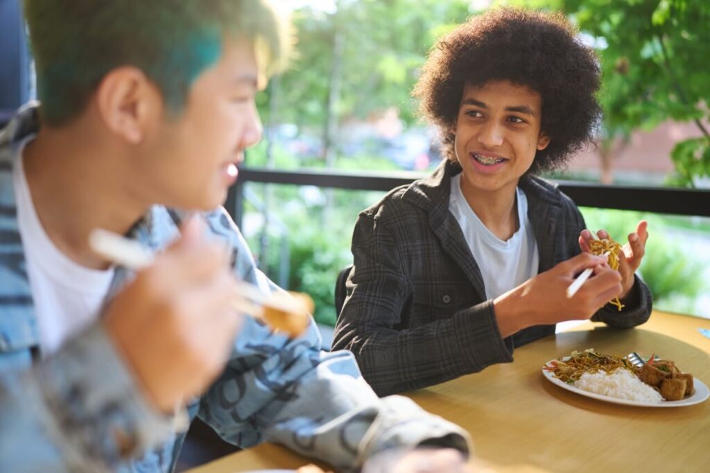 Two high school boys talk together during lunch.