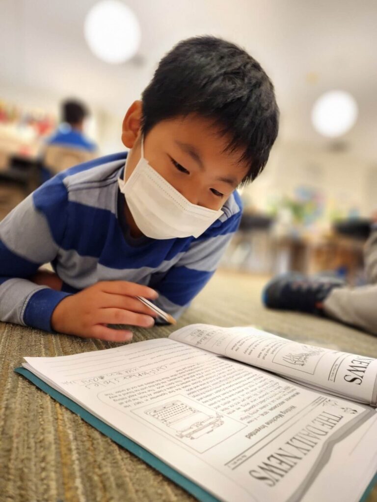 A student in a mask reads his notebook.