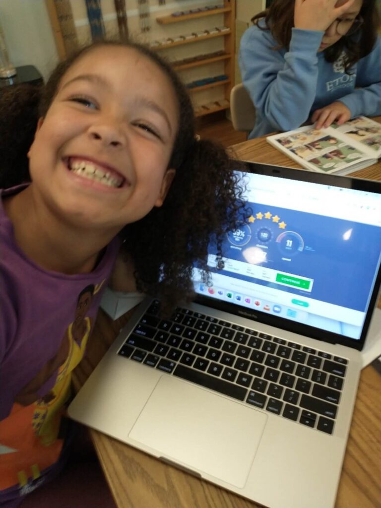 A girl smiles with her laptop.
