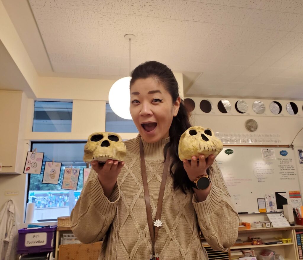 An elementary school teacher poses with skulls that students made.