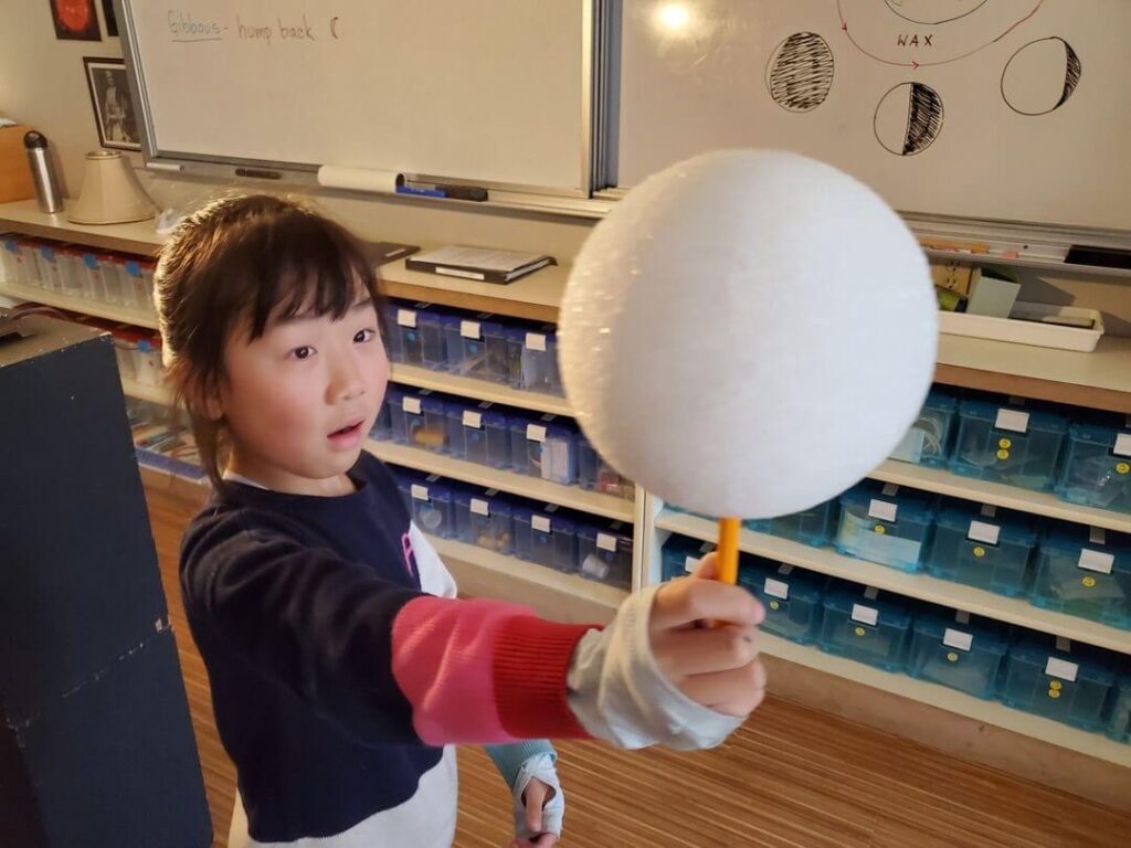 An elementary student plays with a styrofoam bubble