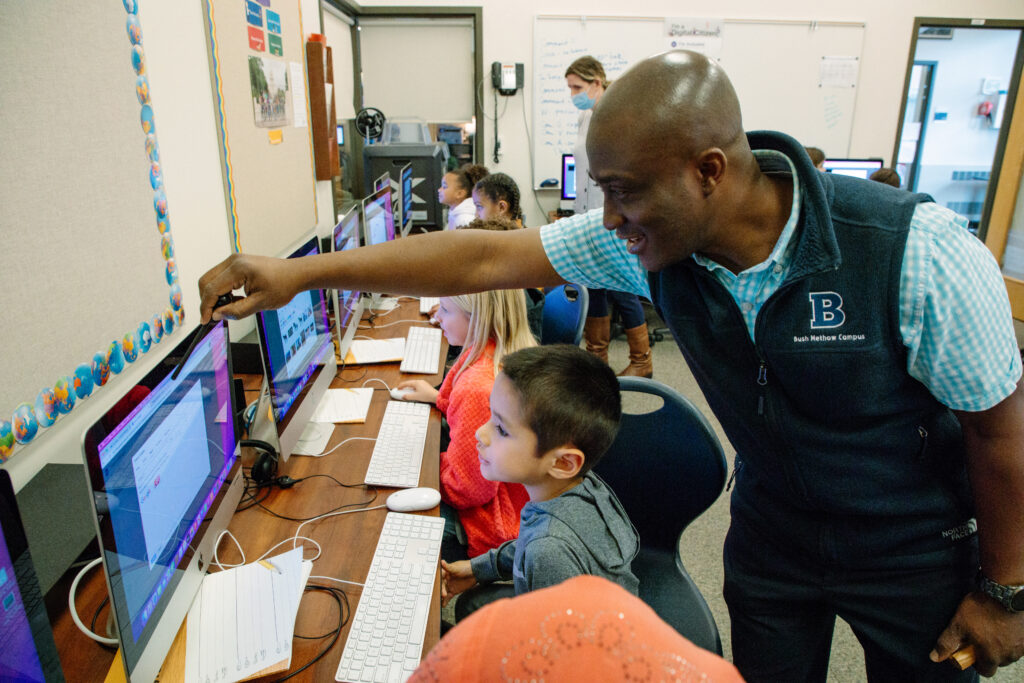 A teacher helps a student learn to use a computer.